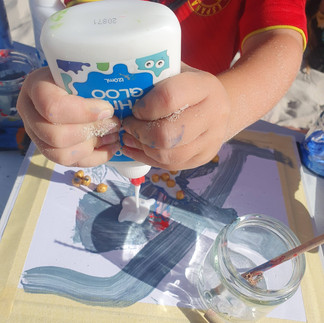 Child is using fine motor skills to add glue to their picture