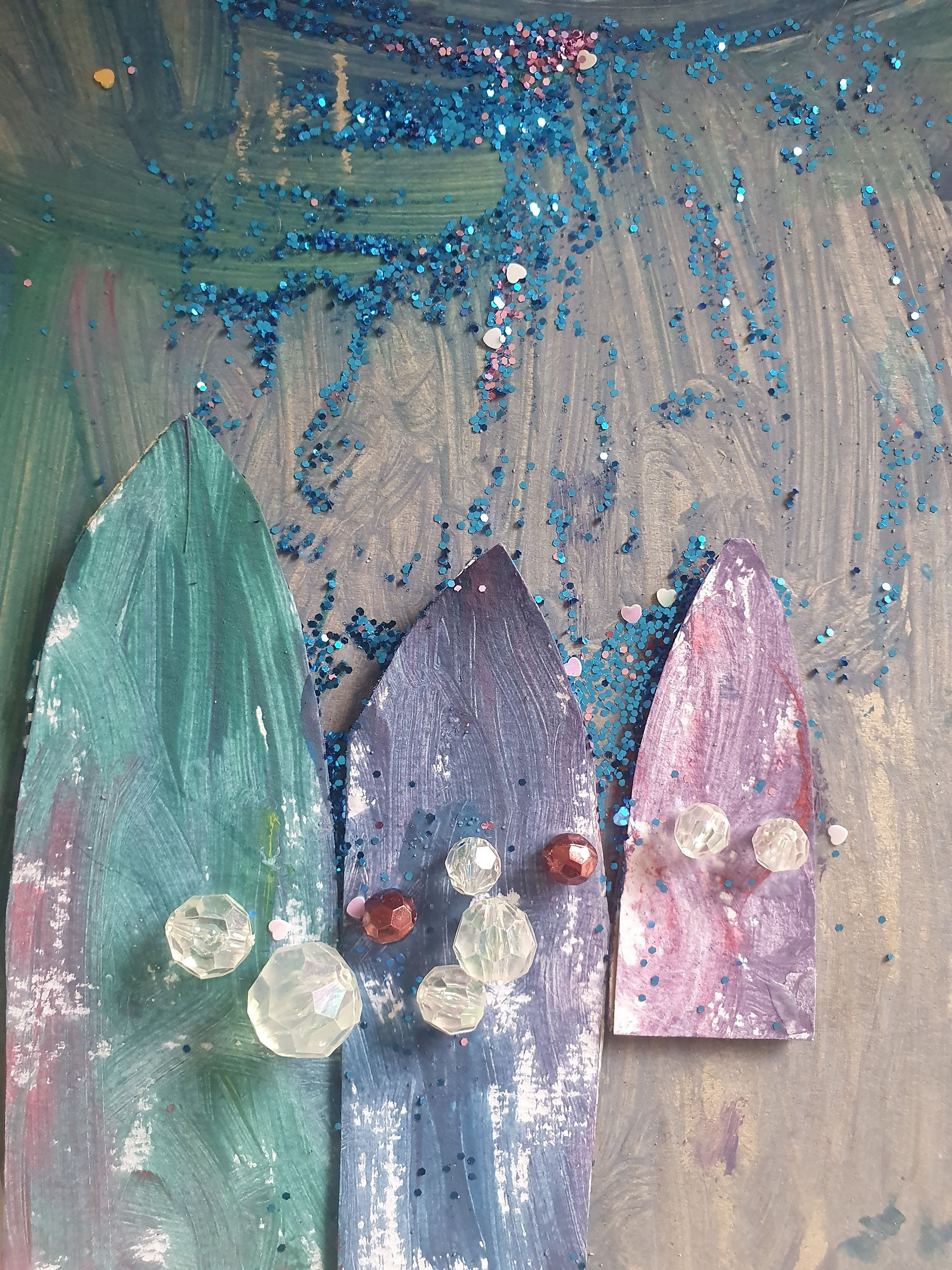 painting of 3 surfboards in carying shades of blue and purple covered with turquoise glitter and mini clear beads