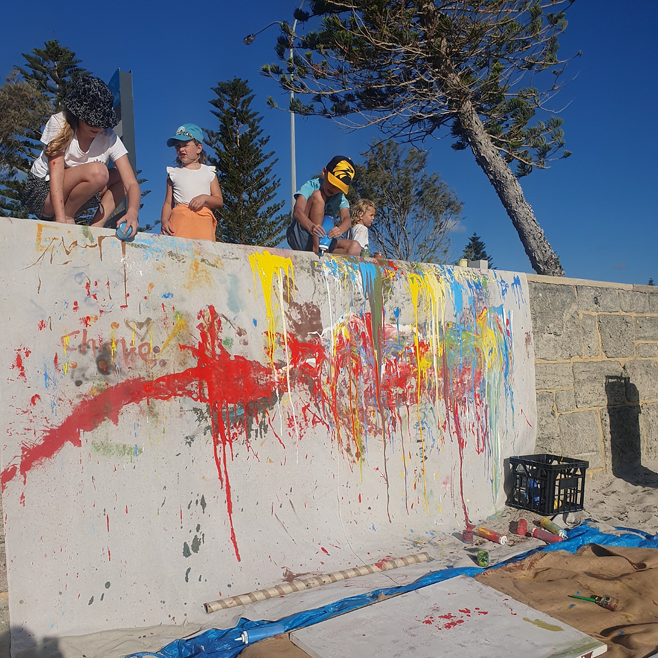 Children mid play on the paint waterfall sitting and standing up squeezing paint down the wall.