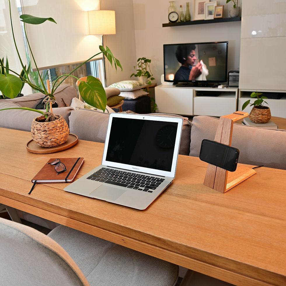 Thumbnail: 2-in-1 Headphone Stand with Wireless Phone Charger with phone held to magnetic charger on desk with laptop