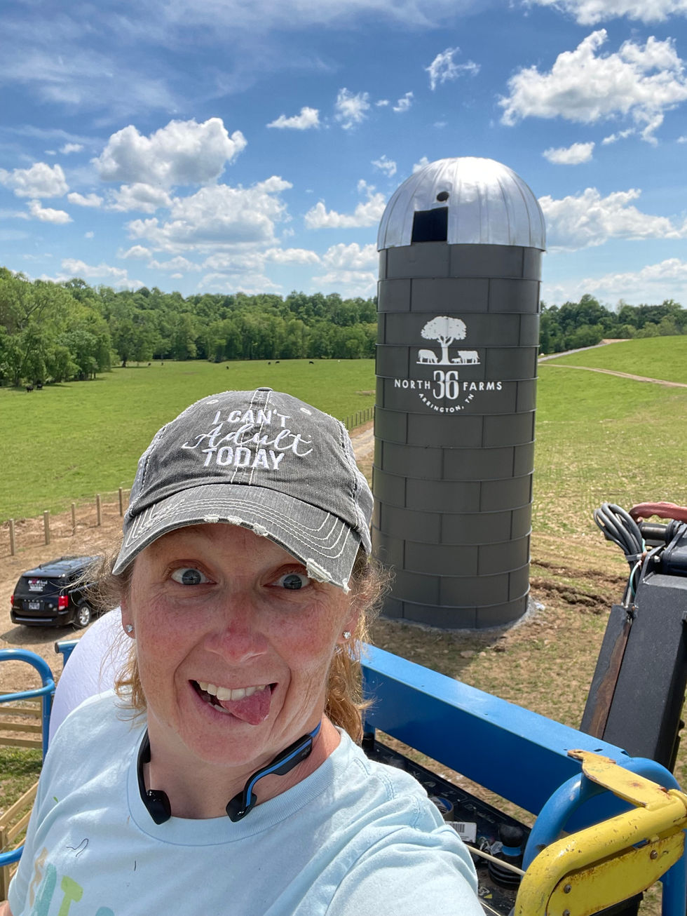 Muralist Painting silo logo mural in Arrington, Tn