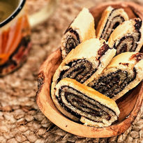 Slices of vegan shortcrust roulade with chocolate swirls, served in a wooden dish beside a cup of coffee.
