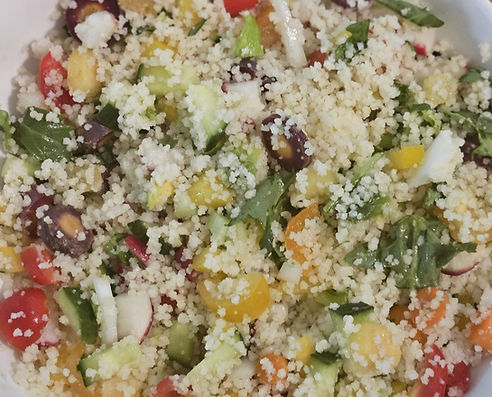 Colorful vegan couscous salad with cherry tomatoes, cucumbers, bell peppers, and fresh herbs