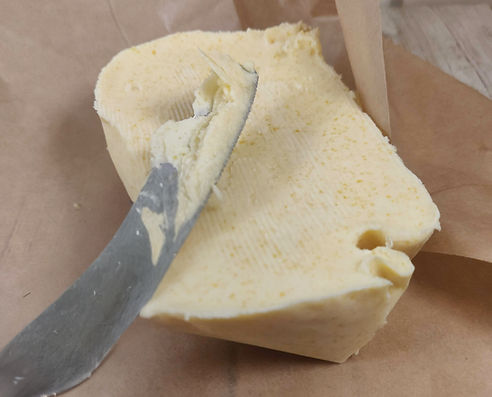 Slice of creamy vegan homemade butter being spread with a knife on parchment paper