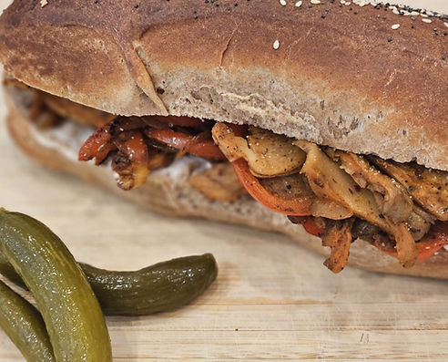 Close-up of vegan shawarma sandwich with mushrooms and peppers on a sub roll.