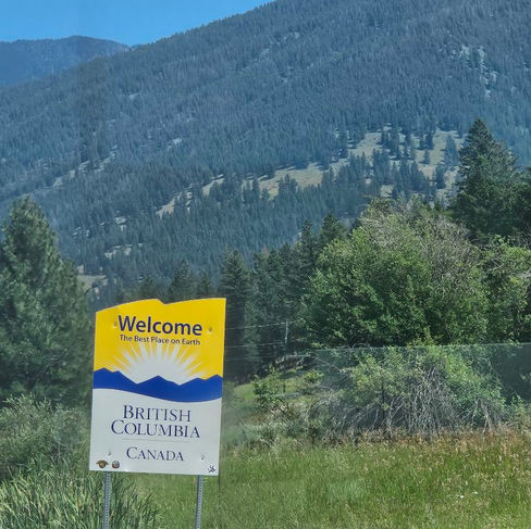 Welcome to British Columbia road sign with mountains and trees in the background