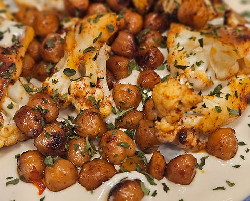 Roasted chickpeas and cauliflower served over a creamy tahini base, garnished with fresh herbs.