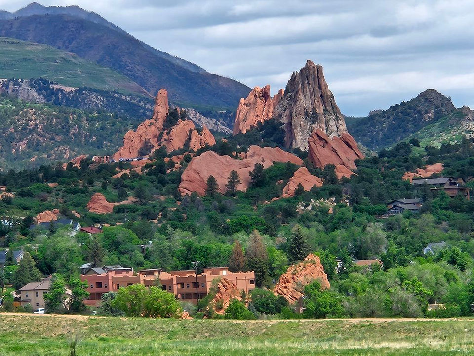 Garden of the Gods, CO on a cloudy day, with a green mountain in the back
