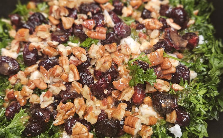 Vegan parsley salad topped with walnuts, dried berries, and creamy dressing.
