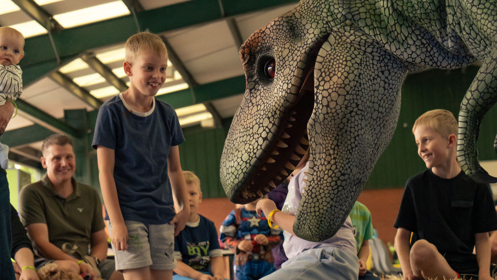 Boy laughs at animatronic dinosaur stood infront of him