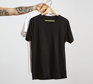 tattooed-biker-hand-holds-wooden-hangs-with-blank-black-white-t-shirts-from-premium-thin-c