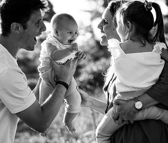 Family of four sharing laughter with their baby in their arms during a photo shoot in the Manantiales forest at sunset – Onedrop Photography
