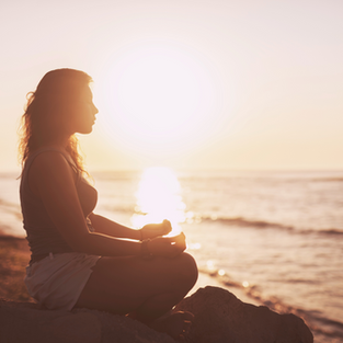 Woman meditating on the beach at dawn