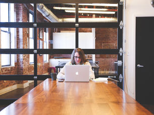 An employee working on a laptop in a conference room, symbolizing communication, leadership trust, and overcoming employee silence.