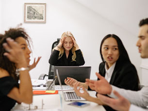 Team members discussing a project during a workplace meeting, illustrating how assumptions in workplace communication can lead to misunderstandings and confusion.