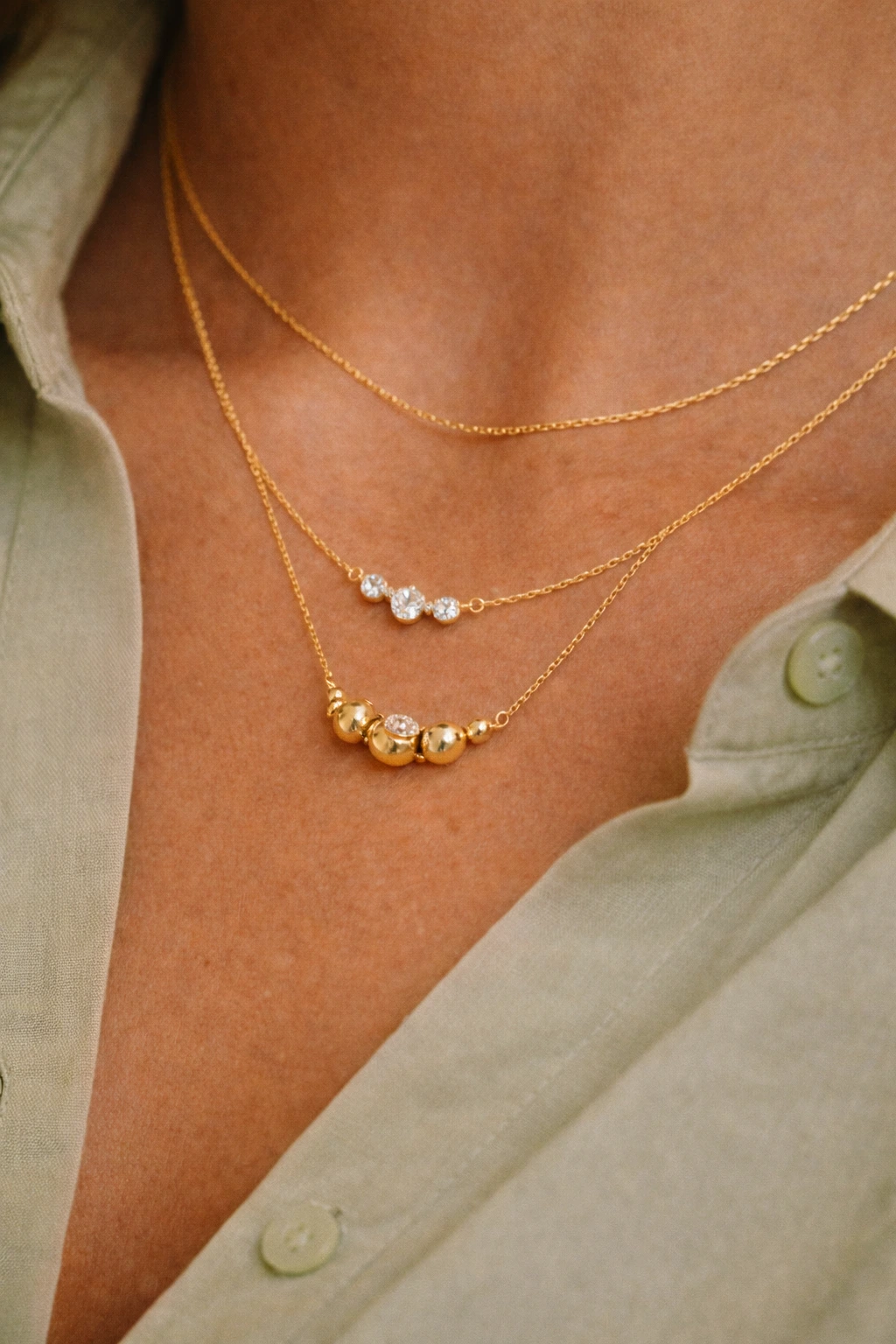 plano detalle del cuello de una mujer que lleva tres collares dorados