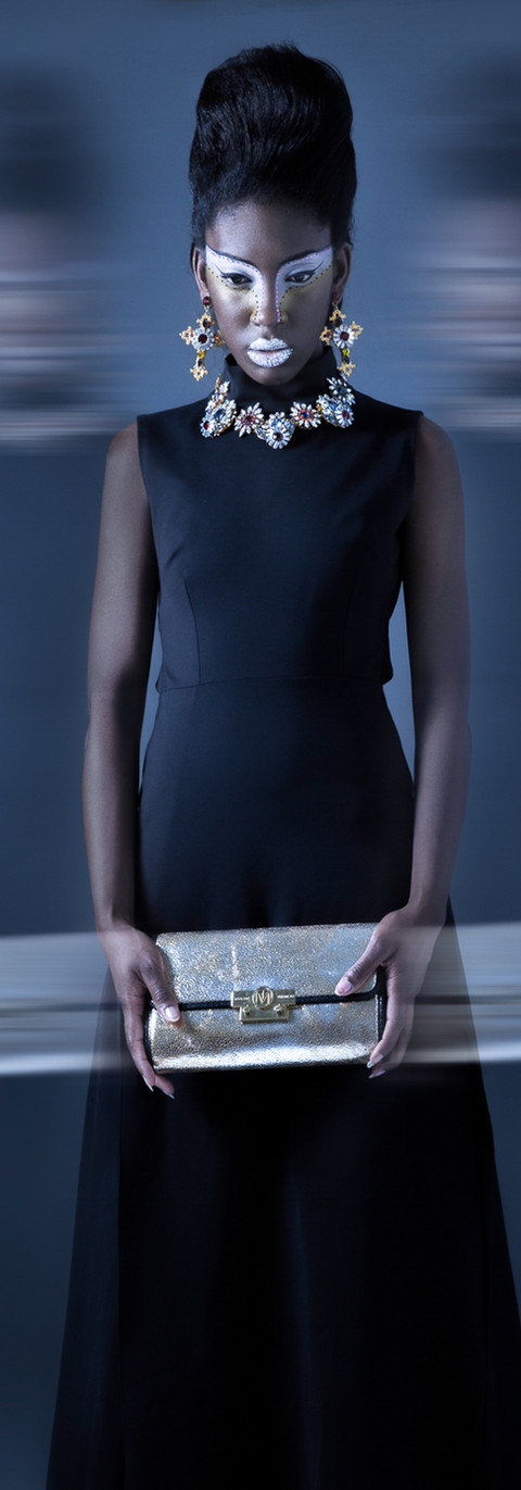 Fotografia creativa en movimiento de modelo de moda (mujer) con vestido negro y joyería plateada sobre fondo azul