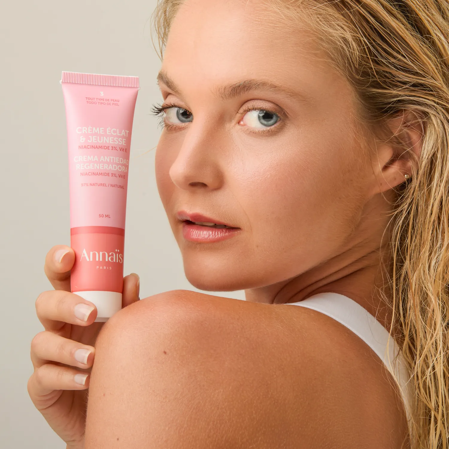 chica rubia con top blanco sujeta un bote de crema de color rosa