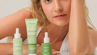 Blonde girl wearing a white top with three green cream jars