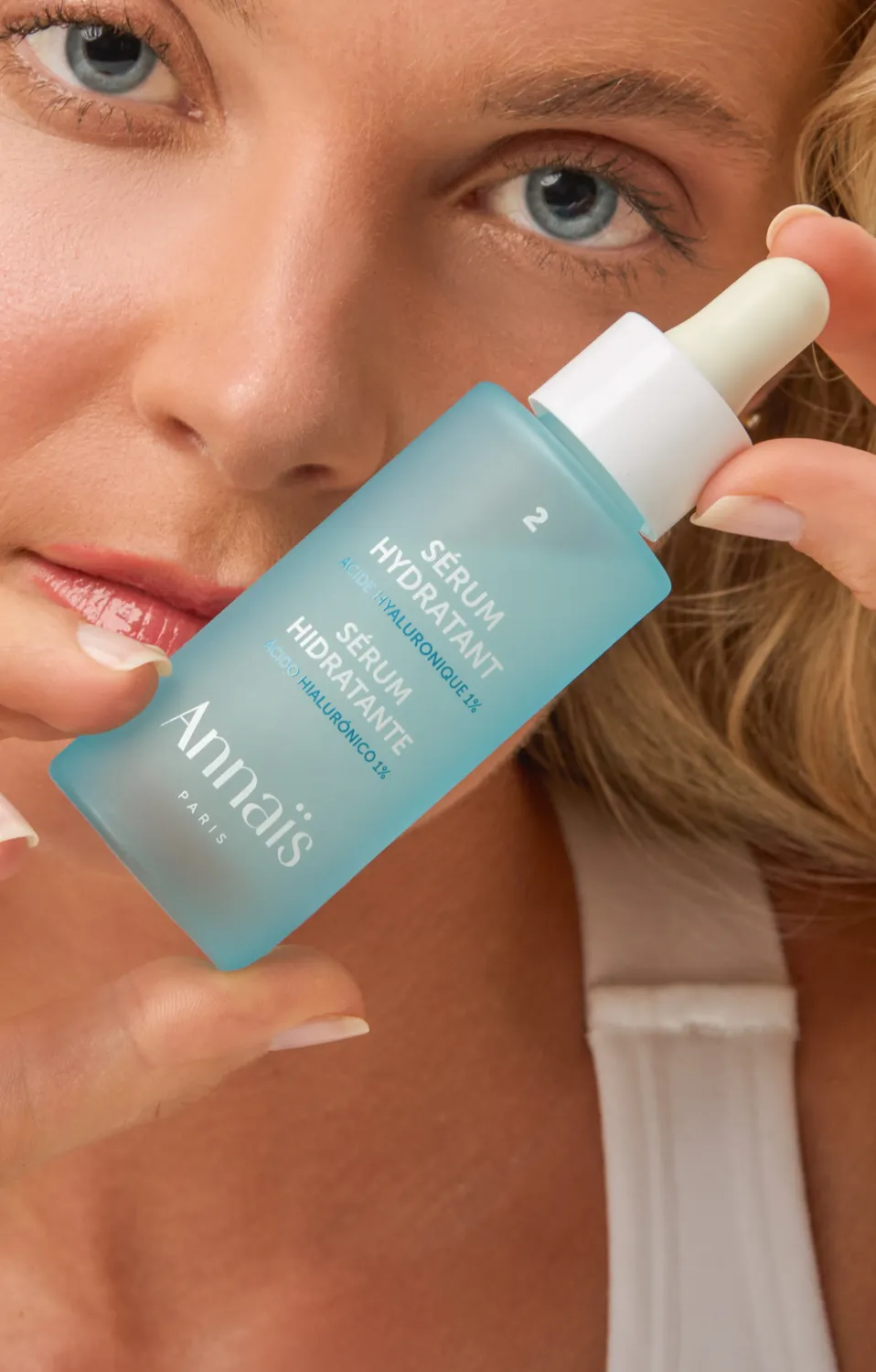 chica rubia con top blanco sujetando un bote de crema azul