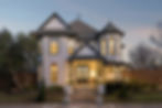Modern two-story Victorian house with lit windows at dusk