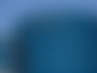 Prédio moderno com fachada azul espelhada e palavra "ORACLE" no topo. Fundo de céu claro. Estrutura cilíndrica e linhas horizontais.