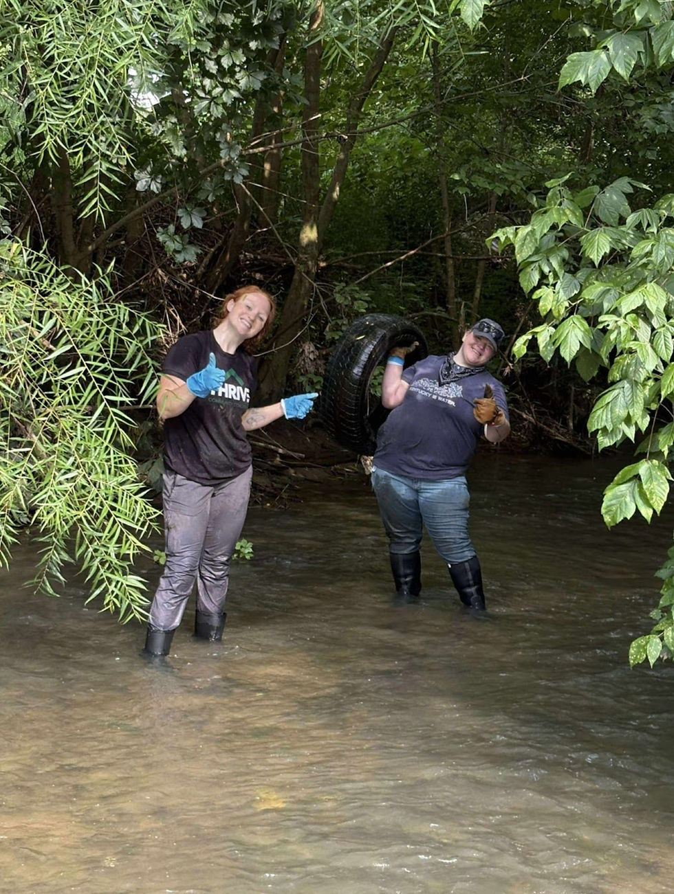 Kayla Corbiere (Thrive Community Coalition) and Madison Mooney (LiKEN) pulling tires from the creek in Inez. Photo by a cleanup volunteer.