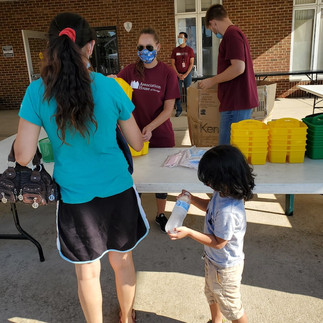 A mother and her child grabbing school supplies from volunteers. 