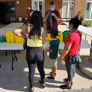 2 hispanic women and 1 little hispanic boy grabbing school supplies from volunteers. 