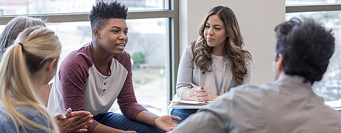 Young black mail in a support group sitting next to a female counselor.