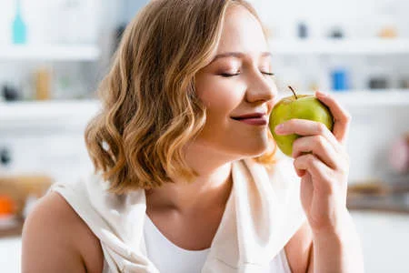 Young-woman-with-closed-eyes-smelling-green-apple.webp