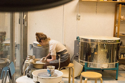 alt="Lucie Eleme, céramiste artisanale à Paris Ménilmontant dans son atelier de poterie"