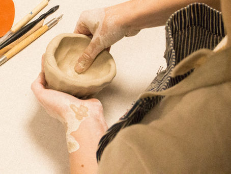 un éléve modelant de la terre lors d'un cours du soir de poterie dans un atelier de céramique à Ménilmontant