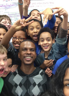 Rey Grandoit with elementary students smiling at the camera.