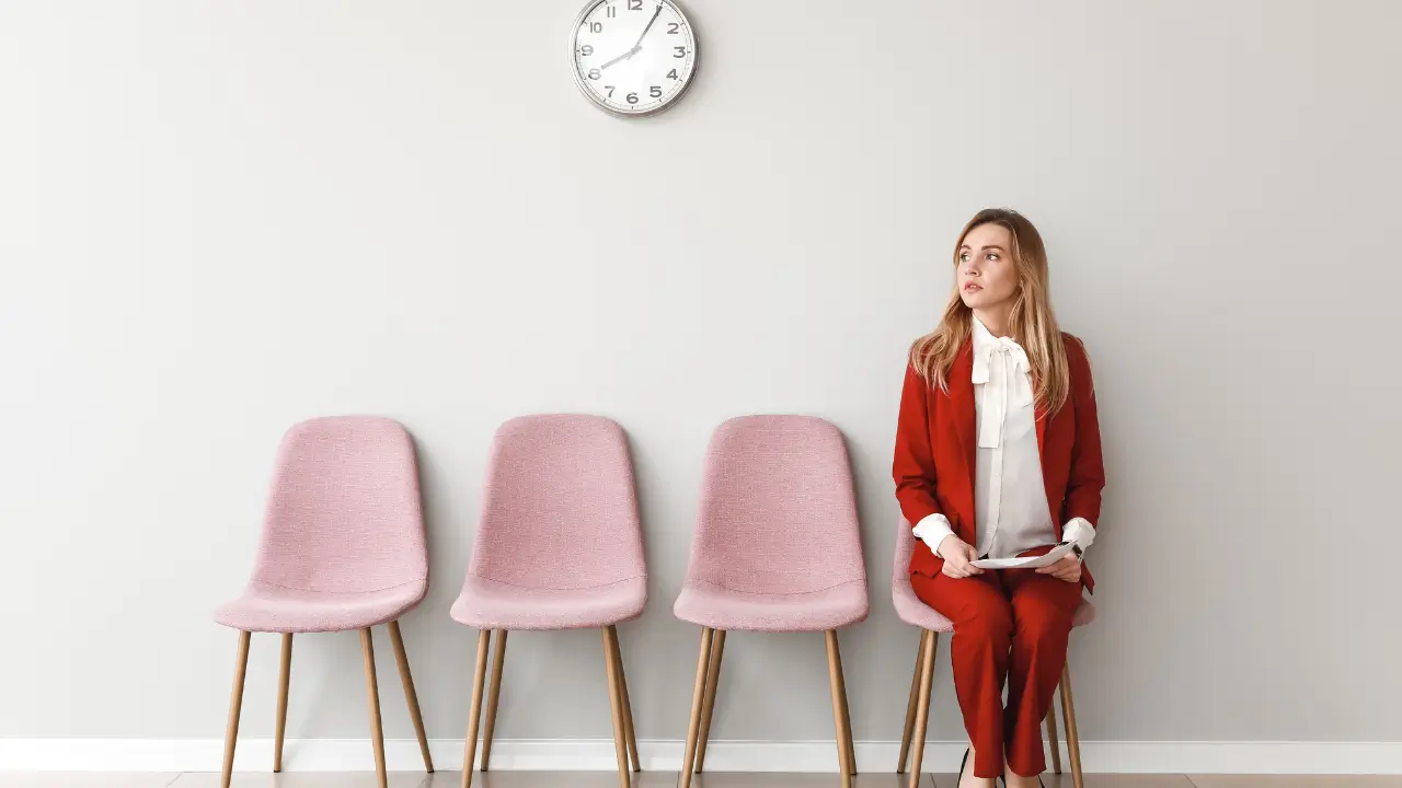 Joven con traje rojo esperando en una sala de espera