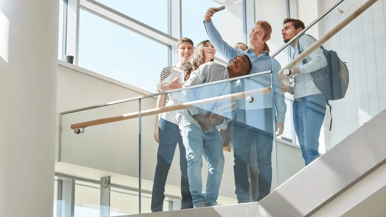 Alumnos tomándose una selfie en unas escaleras frente a una ventana