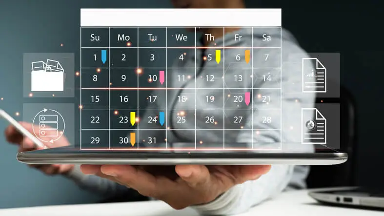 Persona sosteniendo una tablet sobre la cual vemos un holograma de calendario