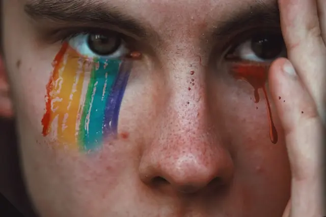 Persona con la bandera del Orgullo Gay pintada en el rostro