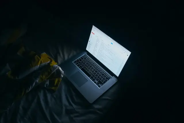 Una laptop sobre una cama en una habitación oscura