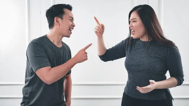 Dos personas discutiendo y señalándose con el dedo