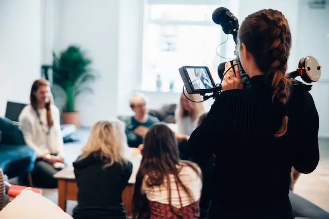 Persona grabando con una cámara de vídeo una reunión de trabajo