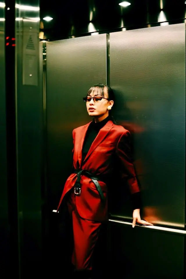 Mujer con traje rojo y lentes de sol en un elevador