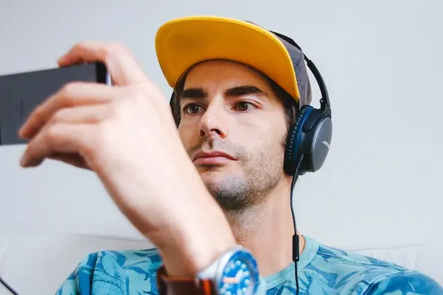 Joven con gorra y audífonos mirando un vídeo desde su smartphone