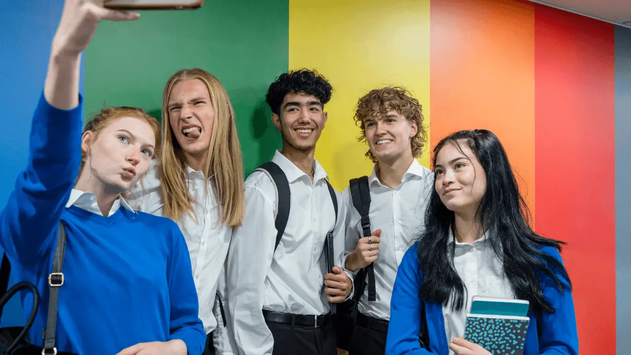 Estudiantes tomándose una selfie frente a una pared colorida