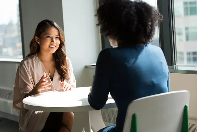 Dos mujeres hablando sentadas frente a una mesa