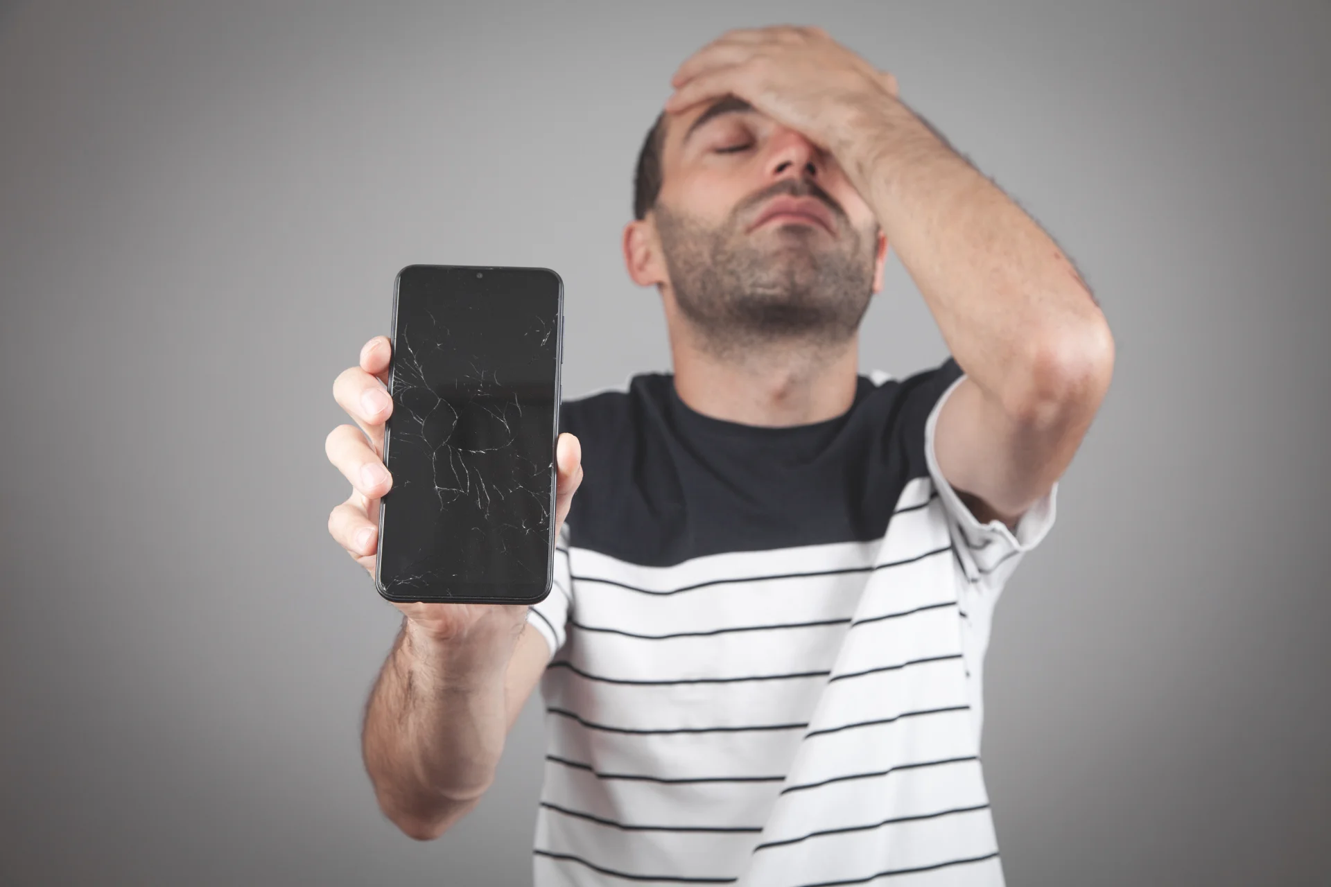 Hombre muestra preocupado un smartphone con la pantalla rota