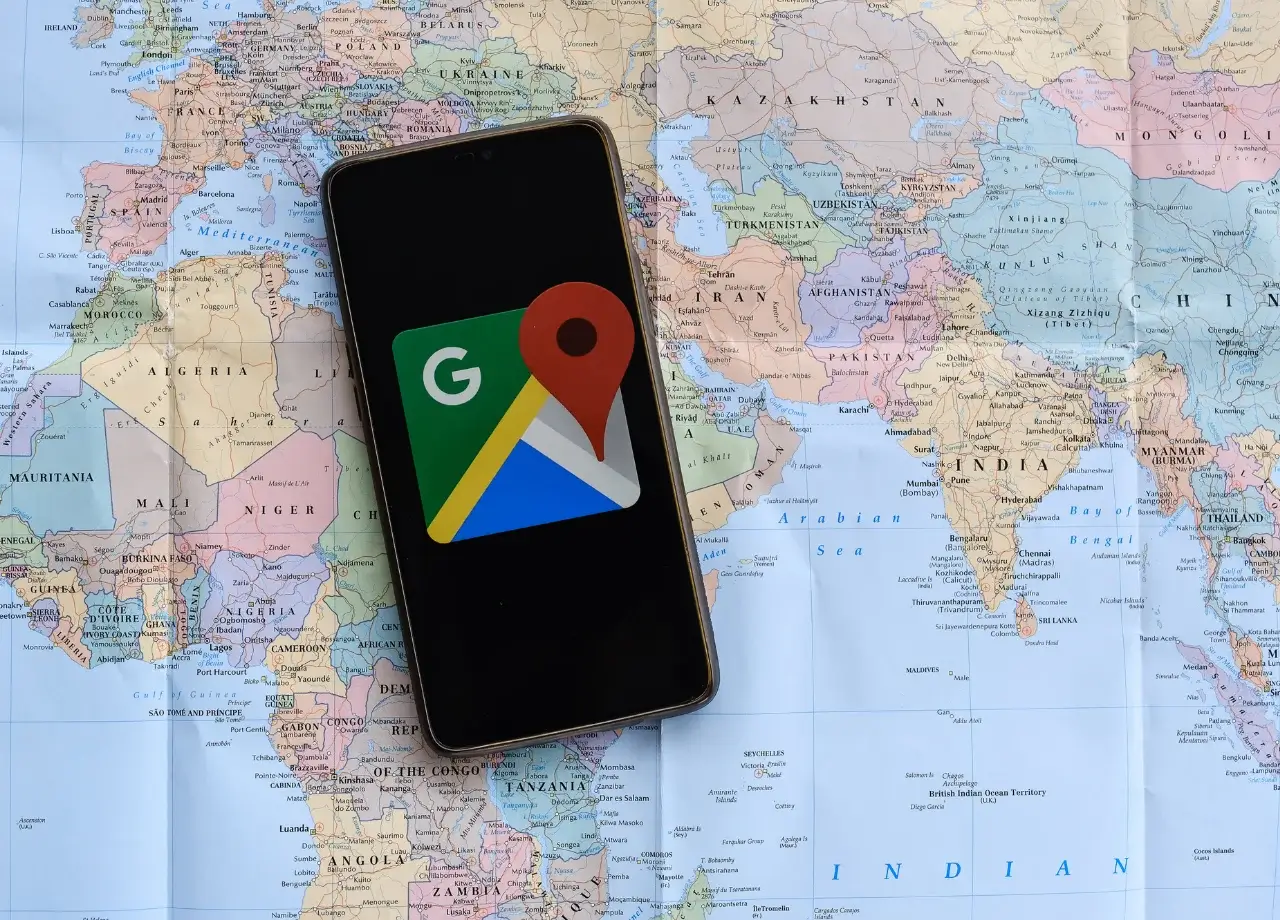 Smartphone mostrando logo de Google Maps sobre mapamundi