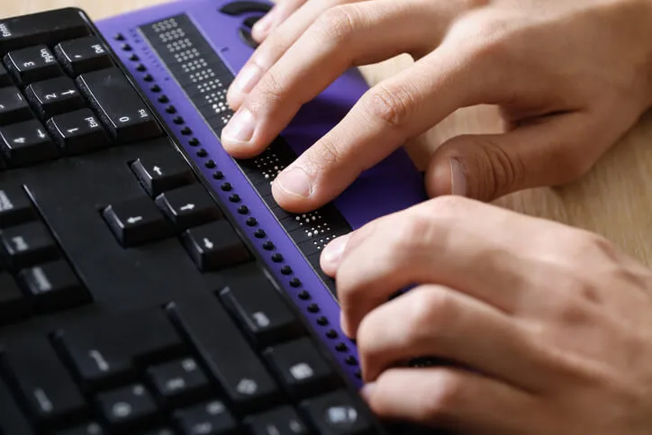 Persona interactuando con un teclado en braille