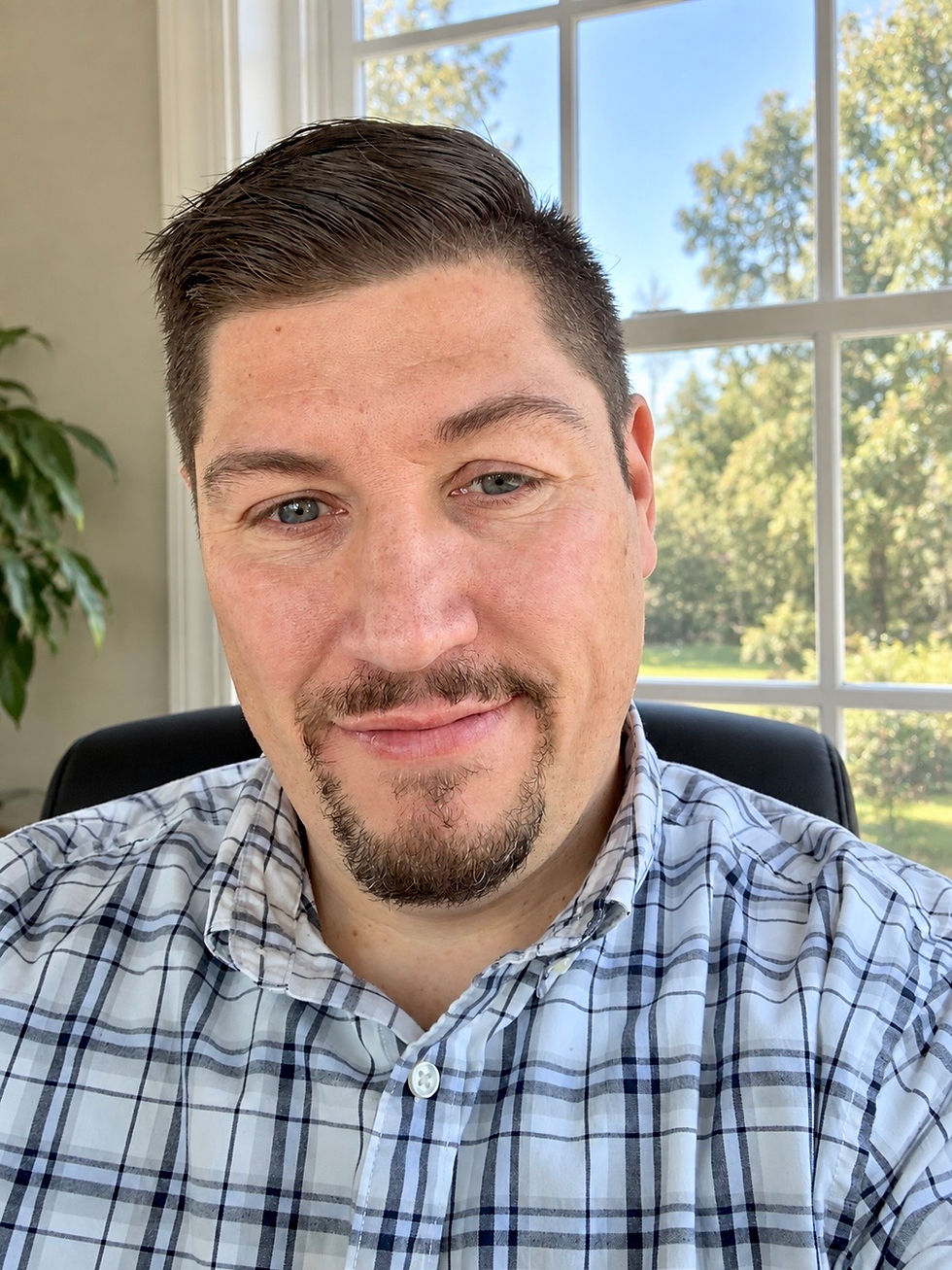 Portrait of a man in a plaid shirt with a goatee.