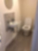 A bathroom with a toilet and wall-mounted sink on a grey tiled floor